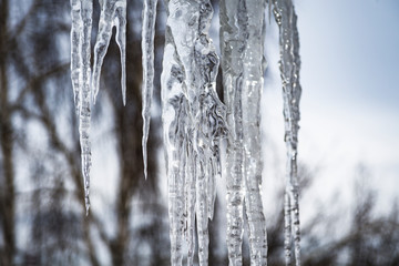 A huge icicle hangs from the roof of the building. Concept: the threat to the lives of passers-by.