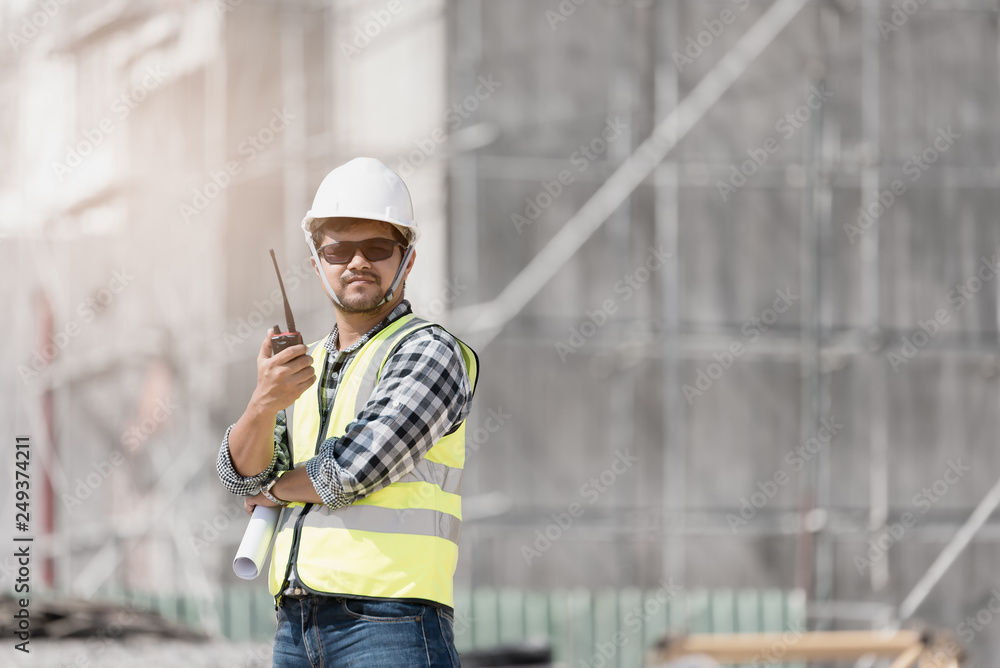 Wall mural Civil engineer checking work with walkie-talkie for communication to management team in the construction site