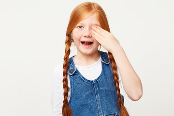 Happy glad red-haired girl at the reception at the oculist, covered right eye with a palm, the...