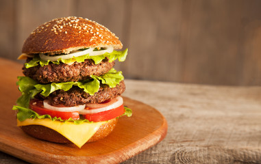 Tasty burger with cheese on wooden table