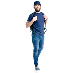 Fototapeta premium A man photographer in jeans and cap, black backpack goes walking looking on white background isolation
