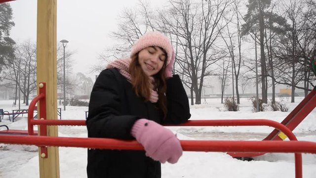 Young girl in black clothes and hat on the Playground in winter.