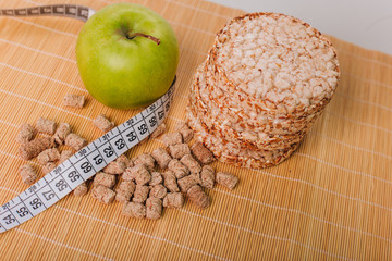 Green apple wrapped with a centimeter, and bran. Healthy food. Diet for weight loss. Dietary bread