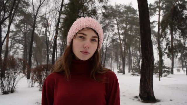 Cute beautiful young girl in hat and red sweater in winter outdoors.