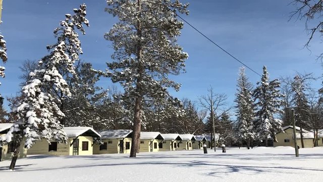 Row of yellow summer cabins covered in snow on a sunny day in Minnesota.