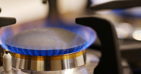 Stove burner igniting into a blue cooking flame