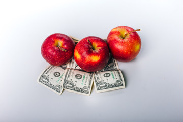 apples on money. Fruit stand on a white table. Dollars under red apples