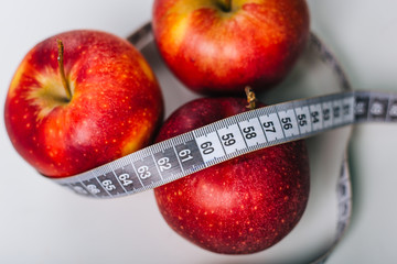 Red apple wrapped centimeter lies on a white table. Apple diet