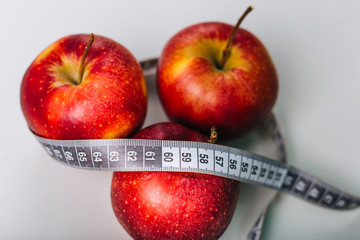 Red apple wrapped centimeter lies on a white table. Apple diet