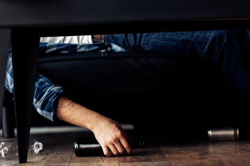 cropped view of man lying on sofa near bottles after party