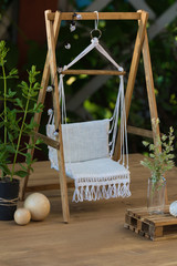 Cozy house terrace with wooden garden swing with white linen upholstery, outdoor plants and pallet table, Dollhouse garden furniture for summertime relax