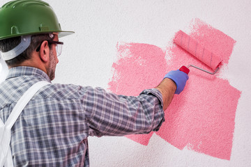 Professional house painter at work painting the wall © francescomou
