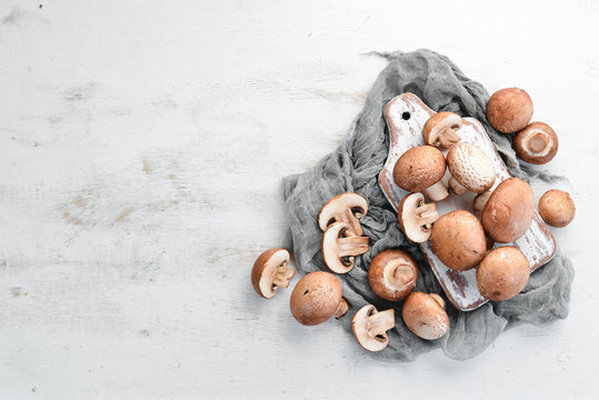 Mushrooms on a white wooden background. Champignons Top view. Free copy space.