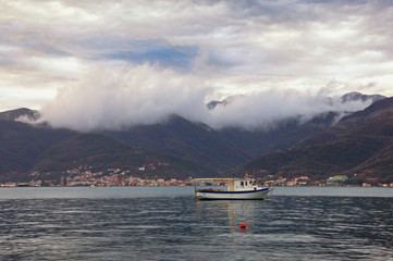 Beautiful  Mediterranean landscape on cloudy winter day. Mountains, sea and one fishing boat on the water .  Montenegro, Adriatic Sea, Bay of Kotor