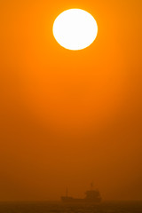 朝の海で太陽の下を行く遠くの船影