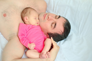 Fototapeta na wymiar A newborn girl falls asleep on her father