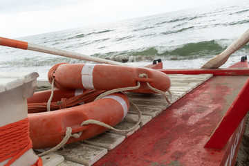 Orange life preserver rings with ropes on a rescue rowing catamaran
