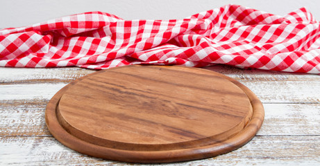 empty pizza board on empty wooden table with tablecloth,napkin - top view