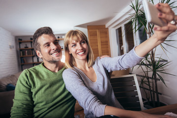 Capturing fun. Beautiful young loving couple bonding to each other and making selfie