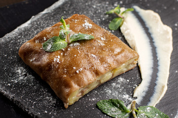 Apple strudel, garnished with mint and sprinkled with powdered sugar.