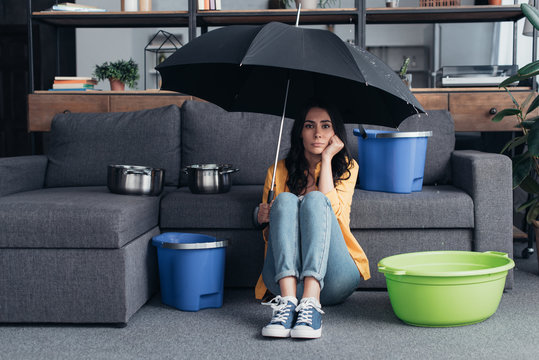 Pensive brunette girl sitting on floor with umbrella