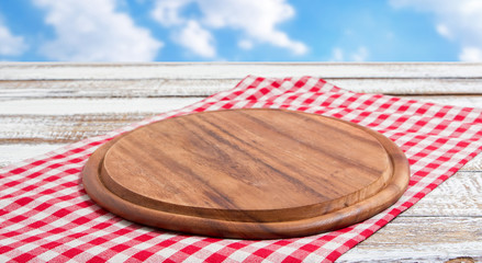 empty pizza board on empty wooden table with tablecloth,napkin - top view