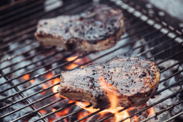 selective focus of juicy tasty steaks grilling on barbecue grid with smoke
