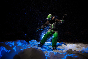 Snowboarder woman dressed in a green sportswear riding on the mountain slope © fesenko