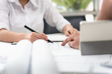 Desk of Architecture and Engineer Designer planning with blueprint on desk in office. Draft and Design in the worksheets with tablet before start-up construction project.