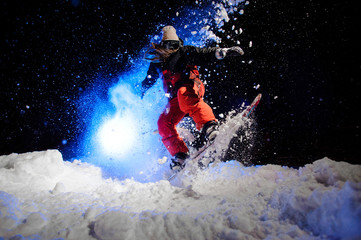 Female snowboarder dressed in a red sportswear jumping on the mountain slope