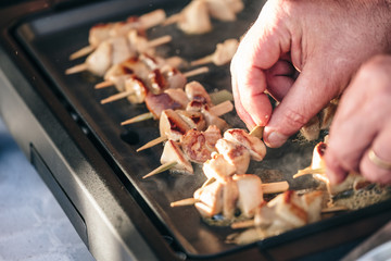 Cook prepares grilled meat on sticks