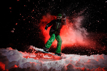 Girl on the snowboard dressed in a green sportswear jumping on the snow