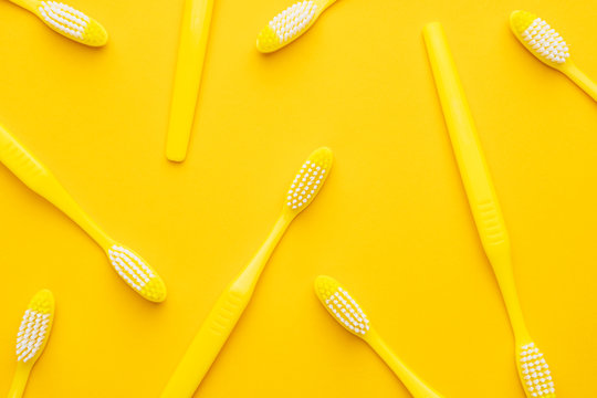 many new plastic toothbrushes on the yellow background
