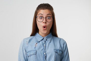 Close up face of a young girl with long hair in glasses looks surprised, amazed, shoked. Woman...