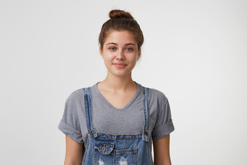 Cute nice and attractive young girl looks affable with a slight smile dressed in denim overall,...