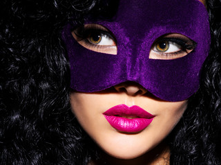 Beautiful  woman with black hairs and violet theatre mask on face.