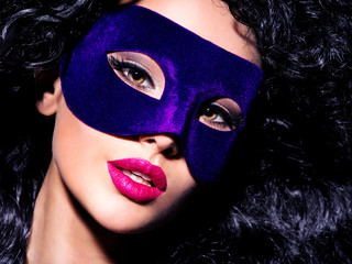 Beautiful  woman with black hairs and blue theatre mask on face.