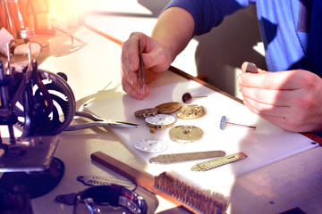 Watchmaker at work in workshop. Workplace of watch repairer. Process of repair mechanical watches..