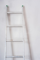 Aluminum ladder leaning against white wall