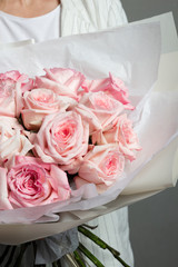 a girl in white clothes is holding a delicate beautiful bouquet of pink roses, in a translucent package, a beautiful flower wrapper, a florist