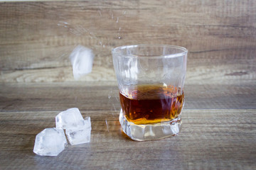 Bourbon Whiskey in a glass with ice on wooden table background
