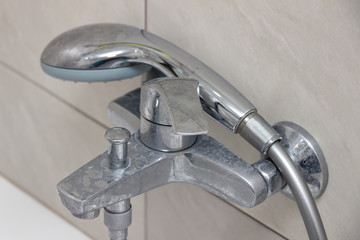 Close-up of shower mixer faucet with limescale, white chalky deposit and stains. Formed on the...