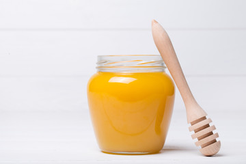 honey dipper and honey in jar on white background