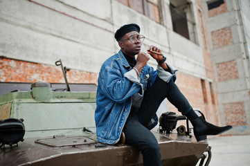 African american man in jeans jacket, beret and eyeglasses, smoking cigar and posed against btr...
