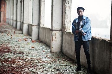 African american man in jeans jacket, beret and eyeglasses at abandoned brick factory.