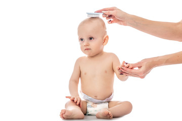 Beautiful baby boy with mother combing isolated on a white background. Mom taking care of infant...