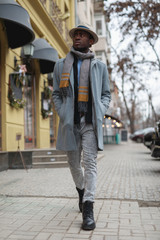 African american man in coat and hat walking along city street