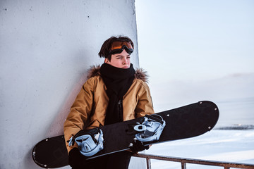 Outdoor activities during the winter holidays. A teenage snowboarder dressed in warm clothes and...