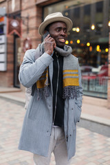 Naklejka premium African man talks by smartphone in city