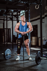 Obraz na płótnie Canvas A strong bodybuilder with a bandage on a leg, holding a sports hammer, warming up before training, injury recovery. Sport, commitment, motivation